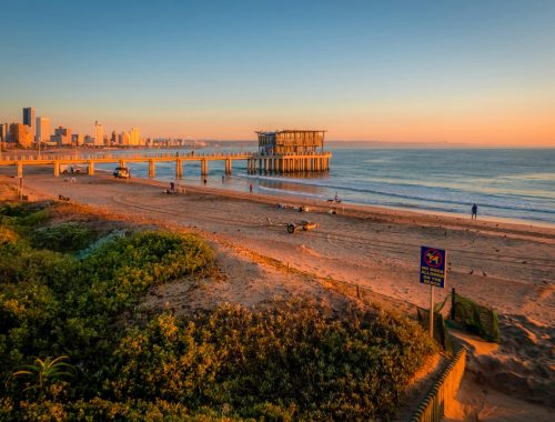 Golden sunrise over Durban's beachfront with a pier extending into the ocean. Perfect coastal view.