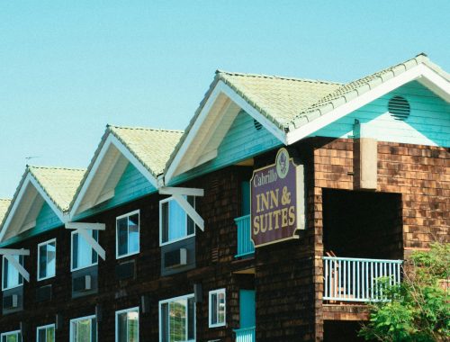 A picturesque wooden facade of Cabrillo Inn & Suites against a clear blue sky.